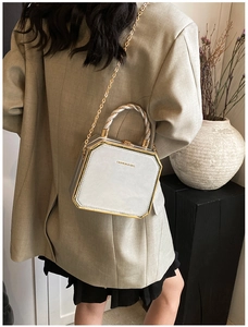 Octagonal silver crossbody bag with metal chain strap worn over a beige blazer