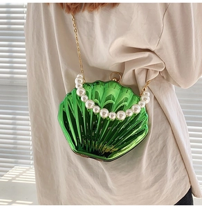 Close-up of a metallic green shell bag with large pearls and gold chain strap