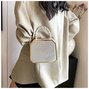 Detailed view of light grey leather handbag with gold metal trim and chain strap