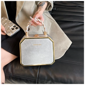 Close-up of silver box bag with gold metal frame and decorative spiral twist handle