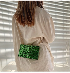 Detailansicht der grünen Acryl-Clutch mit Faltenstruktur und goldener Kette