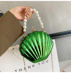 Detail of emerald green shell bag with large pearl handle and golden chain strap