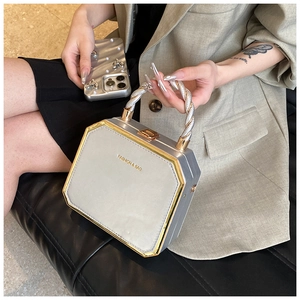 Detail of silver octagonal hard shell handbag with golden metal frame and top handle