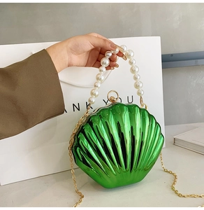 Detail of metallic green shell bag with large pearl handle and golden metal chain strap