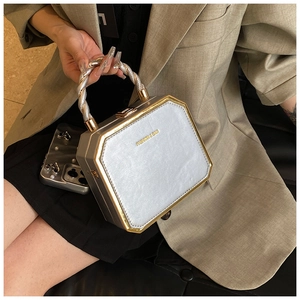 Detailed close-up of a silver hexagonal handbag with gold trim and twisted handle