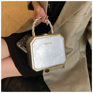 Detail of grey octagonal structured handbag with golden frame and silver rope handle