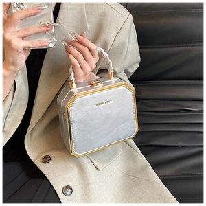 Detail of silver octagonal hardshell handbag with gold metal trim and twisted handle