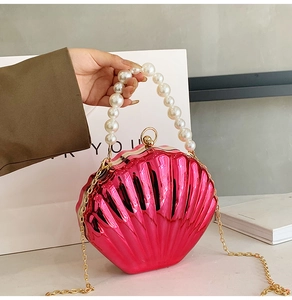 Detail of shell-shaped evening bag in metallic rose red with pearl handle and chain