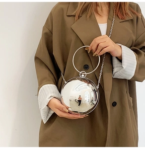 Mirror silver sphere clutch bag with metal ring handle and chain shown on a model