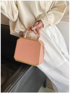 Detail of a pink hexagonal box bag with golden frame and twisted top handle