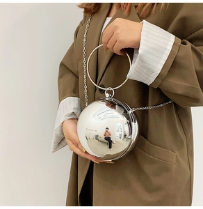 Dettaglio borsa a sfera argento con finitura a specchio e manico circolare in metallo