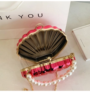 Detail of rose red shell bag featuring premium pearl handle and gold metal hardware