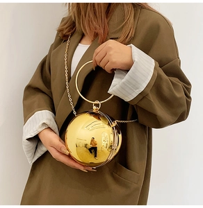 Dettaglio della borsa da sera sferica dorata con manico ad anello e catenella