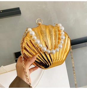 Detail of shell-shaped evening bag in gold metal with pearl handle and chain strap