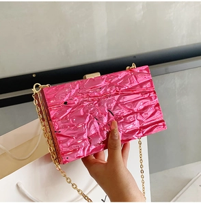Detailaufnahme der pinkfarbenen Abendtasche mit Metallic-Effekt und goldener Kette