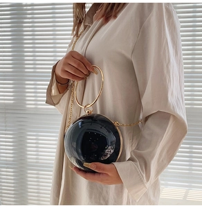 Detailed view of black spherical acrylic evening bag with gold metal ring handle