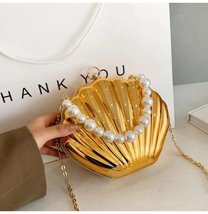 Detail of a shell-shaped gold metallic bag with a pearl handle and chain shoulder strap