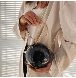 Dettaglio borsa a sfera nera trendy con manico circolare dorato e tracolla a catena