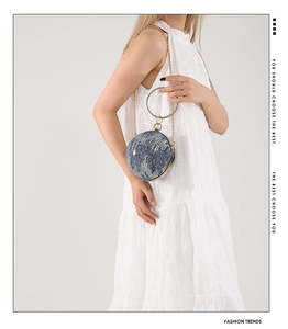 Detail of spherical ball bag with denim texture and golden metal ring handle