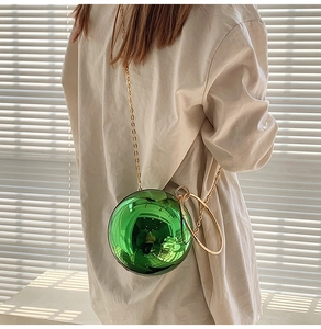 Detail view of the shiny green spherical bag featuring a gold ring handle and chain