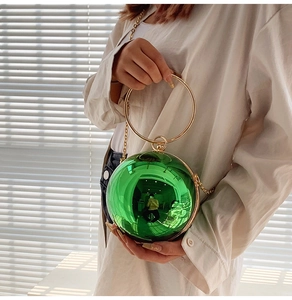 Dettaglio della borsa a sfera verde smeraldo con manico dorato circolare e finitura lucida