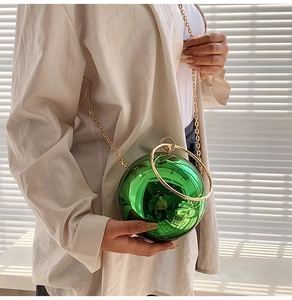 Detail of emerald green spherical acrylic handbag with gold metal ring handles
