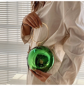 Detail of green sphere clutch bag with gold round handle and metallic mirror finish