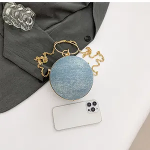 Blue mini spherical glitter evening bag with crystal handle shown beside a smartphone for scale