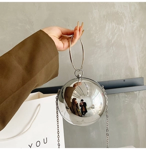 Close-up of a silver spherical evening bag with a metallic mirror finish and ring handle