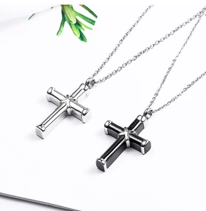 Detail of silver and black cross cylinder necklaces with O-chain on white background