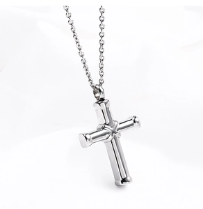 Detailed view of polished stainless steel cross pendant necklace on white fabric