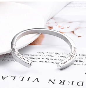 Detailopname van zilveren geborstelde roestvrijstalen armband met gegraveerde tekst