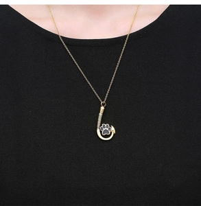 Detail eines goldenen Angelhaken-Anhängers mit schwarzem Pfotenabdruck an einer Kette