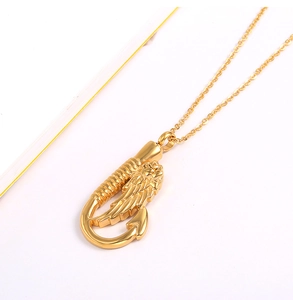 Makroansicht des goldenen Angelhaken-Flügel-Anhängers mit polierter Metalloberfläche