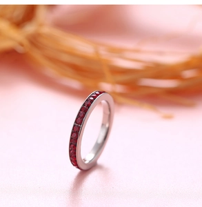 Detailed view of silver ring band featuring meticulously set red circular birthstones
