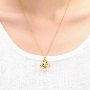Golden angel cremation urn necklace with heart cut-out worn on white linen top