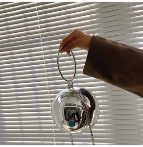 Dettaglio della borsa sferica argento con manico ad anello e tracolla a catena