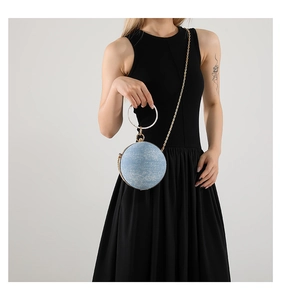 Close-up of a spherical evening clutch with light blue denim texture and silver ring handle