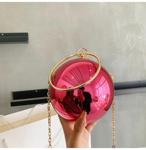 Detail of a metallic spherical evening bag in hot pink with gold chain strap
