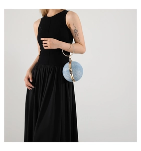 Detail of a blue spherical evening bag with a gold metal ring handle and ball design