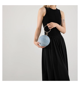 Close-up of light blue glitter sphere clutch with golden bracelet handle and fine texture