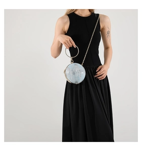 Close-up of a light blue glitter sphere clutch bag with a large gold ring handle and chain