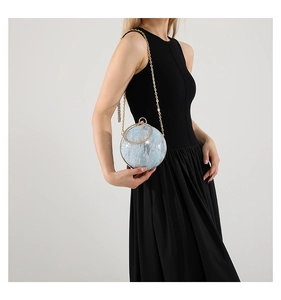 Detailed view of light blue spherical evening bag with sequins and golden metal handle