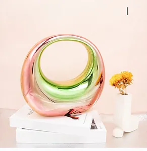 Gros plan sur un vase rond évidé moderne avec une finition irisées colorée sur des livres
