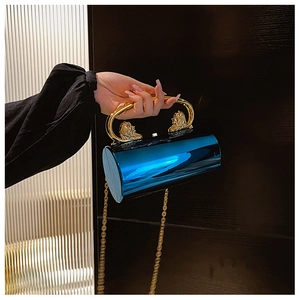 Detail of blue cylindrical mirror handbag featuring gold lion head hardware and chain