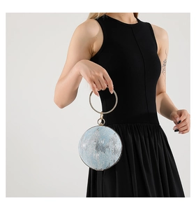 Close-up of sparkling blue sequin round evening bag held by a model in a black dress
