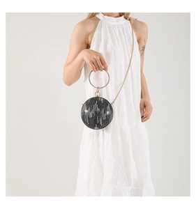 Detail of sequined round evening bag with rhinestone handle and gold metal chain strap