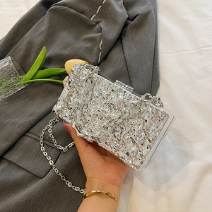 Silver metallic box clutch with lava texture and chain strap held by a person
