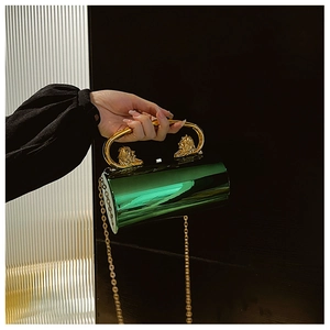 Detail of green acrylic cylindrical clutch with golden lion head accents and metal handle
