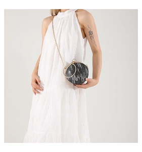 Mini round evening clutch bag with chain strap and metallic ring handle shown on model